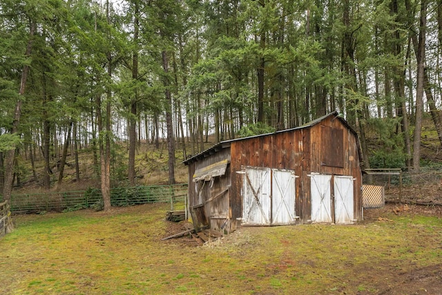 view of barn with a yard and fence