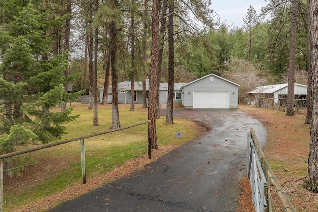 view of front of house with aphalt driveway, a front yard, a garage, and fence