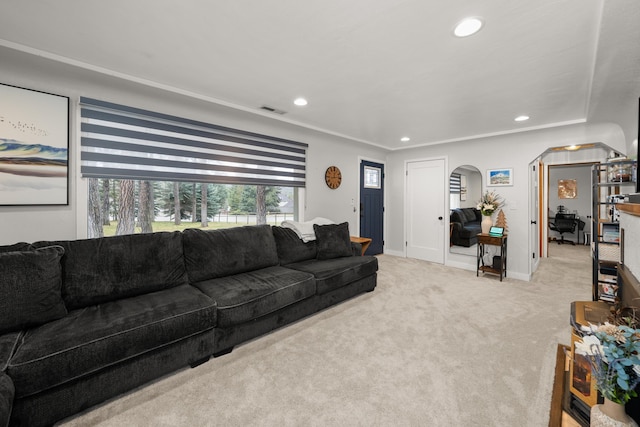 carpeted living room featuring visible vents, baseboards, recessed lighting, arched walkways, and ornamental molding