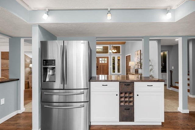 kitchen featuring a textured ceiling, dark countertops, stainless steel fridge with ice dispenser, and white cabinetry