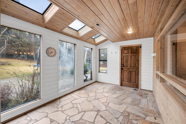 interior space featuring lofted ceiling with skylight, wood walls, wooden ceiling, and stone floors