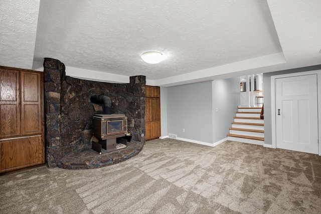 unfurnished living room featuring stairs, baseboards, carpet, and a wood stove