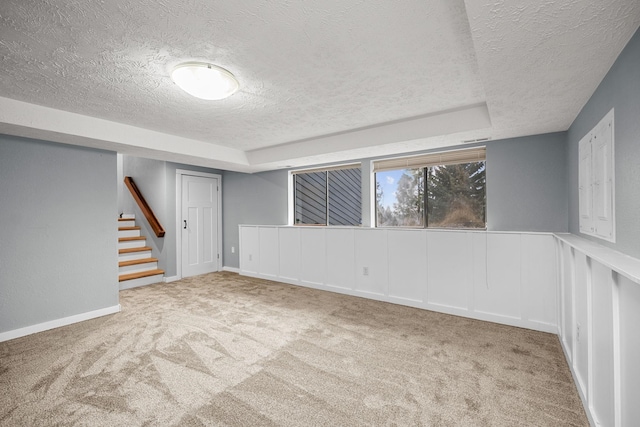 below grade area with stairway, carpet floors, a textured ceiling, and baseboards