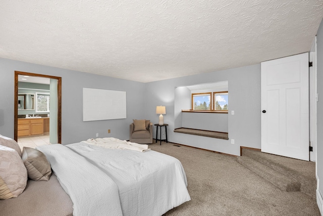 bedroom featuring connected bathroom, multiple windows, a textured ceiling, and light carpet