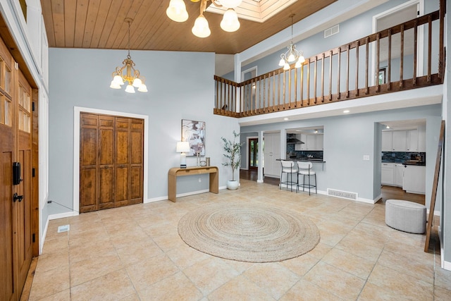 foyer entrance featuring visible vents, baseboards, a notable chandelier, and wood ceiling