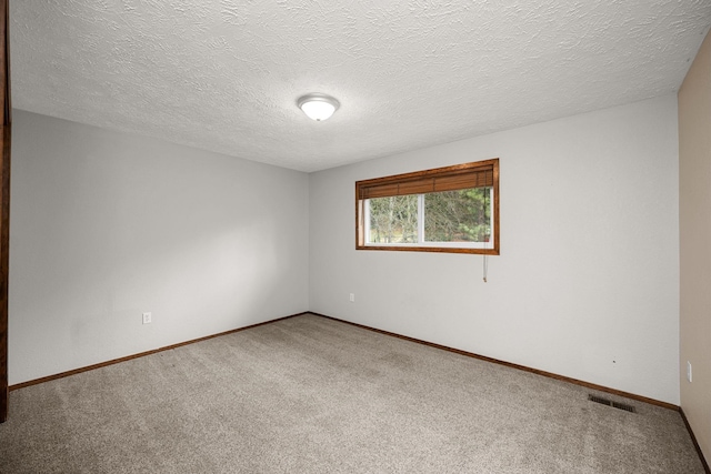 carpeted spare room featuring baseboards, visible vents, and a textured ceiling