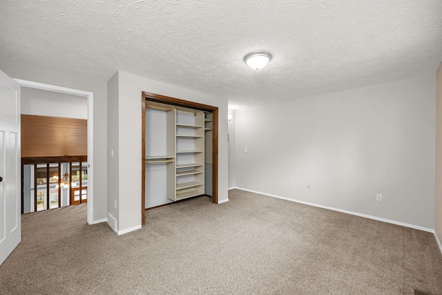 unfurnished bedroom featuring a closet, carpet flooring, a textured ceiling, and baseboards