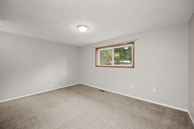 carpeted spare room featuring visible vents, baseboards, and a textured ceiling