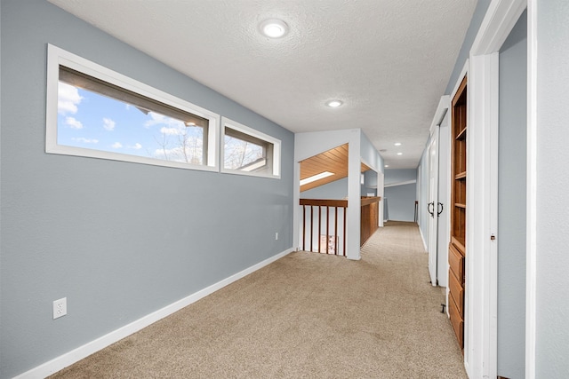 corridor with carpet, baseboards, and a textured ceiling