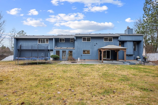 rear view of property with fence, a yard, a chimney, a trampoline, and a patio area