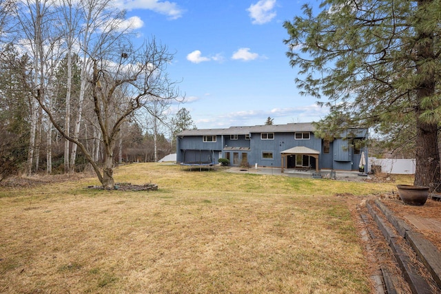 back of house featuring a patio, a trampoline, a yard, and fence