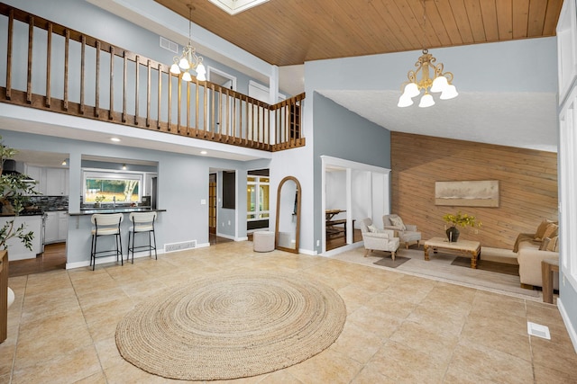 interior space featuring a notable chandelier, visible vents, wood ceiling, and wooden walls