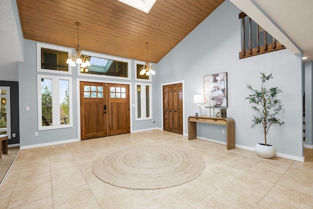 tiled foyer entrance with a skylight, a notable chandelier, wood ceiling, and baseboards