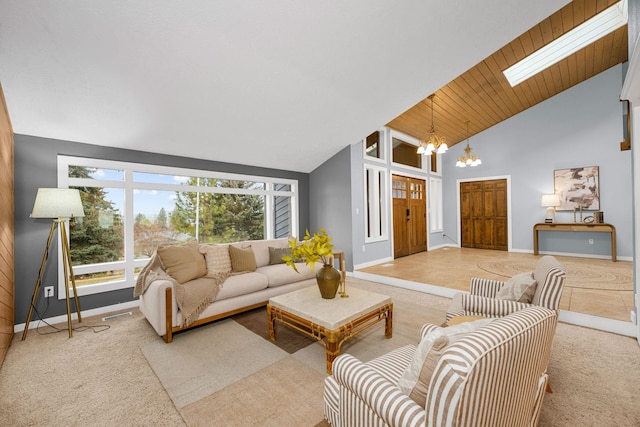 carpeted living room with a skylight, a notable chandelier, baseboards, and high vaulted ceiling