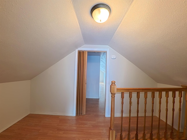 bonus room featuring lofted ceiling, wood finished floors, and a textured ceiling