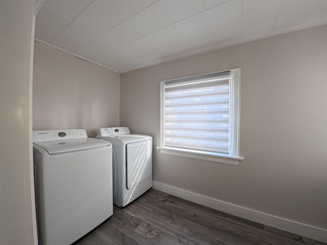 clothes washing area featuring laundry area, washing machine and dryer, dark wood-type flooring, and baseboards