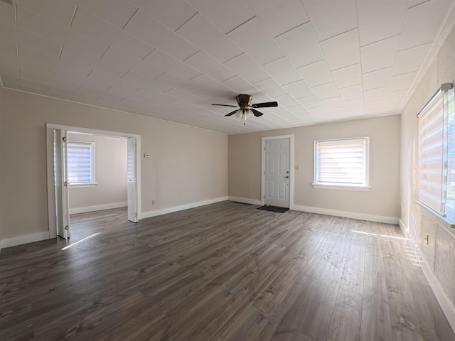 empty room featuring dark wood-type flooring, baseboards, and ceiling fan