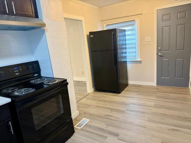 kitchen featuring visible vents, crown molding, under cabinet range hood, light wood-style floors, and black appliances