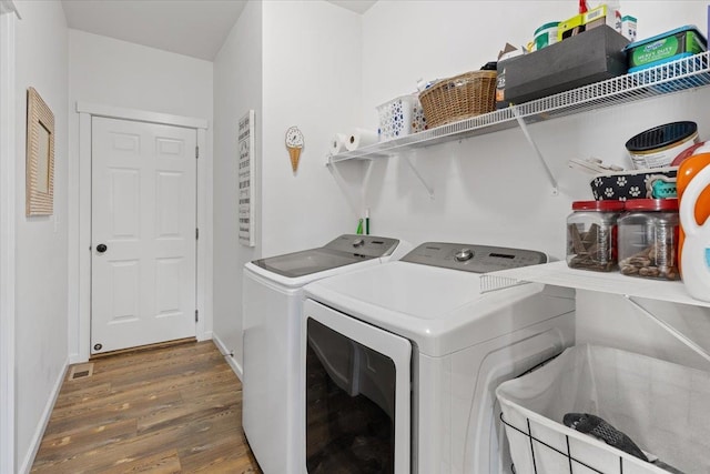 laundry room with laundry area, independent washer and dryer, baseboards, and wood finished floors