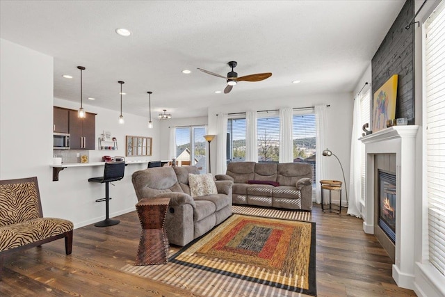 living room featuring a glass covered fireplace, dark wood-type flooring, recessed lighting, and ceiling fan