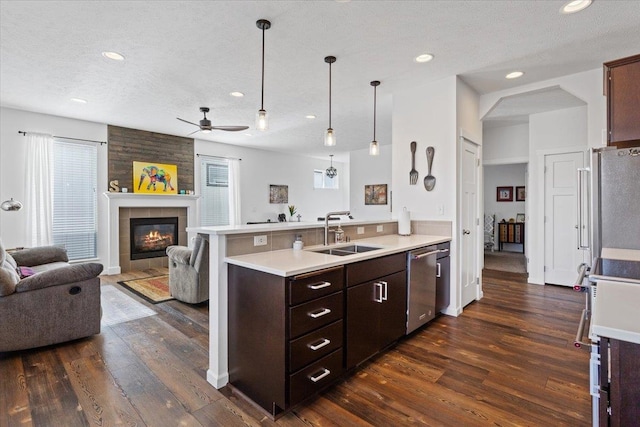 kitchen with a peninsula, a sink, stainless steel appliances, light countertops, and open floor plan