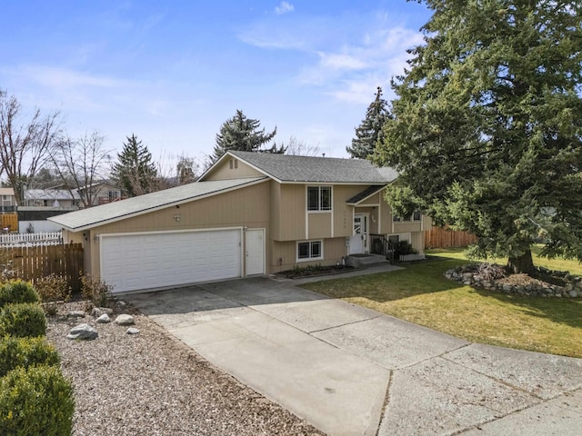 raised ranch with driveway, fence, roof with shingles, a front yard, and an attached garage