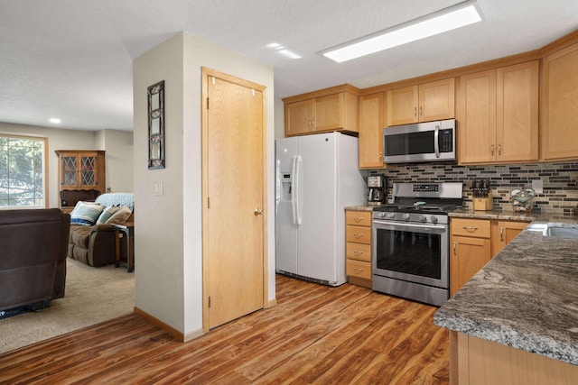 kitchen with tasteful backsplash, open floor plan, stainless steel appliances, and light wood-style floors