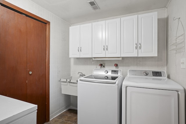 washroom featuring visible vents, washing machine and dryer, cabinet space, tile walls, and a sink