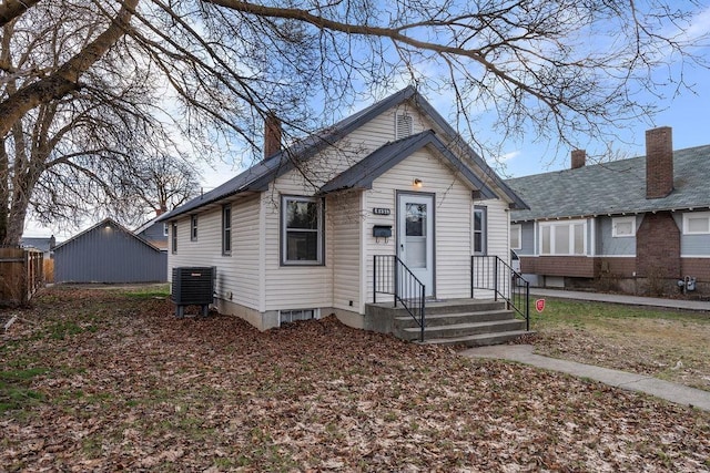 bungalow-style house with central AC unit and a chimney