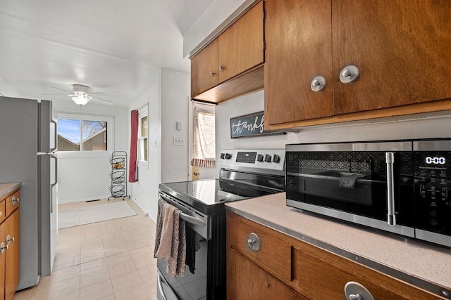 kitchen with stainless steel appliances, ceiling fan, brown cabinetry, and light countertops