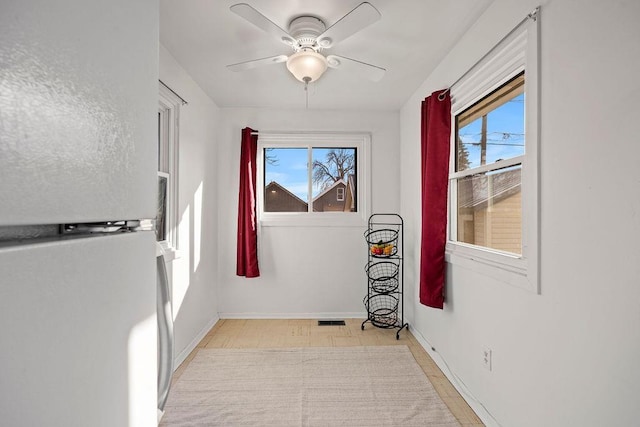 interior space with visible vents, baseboards, light floors, and a ceiling fan