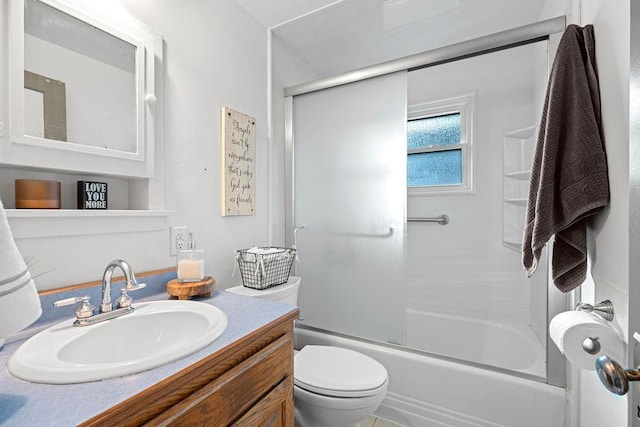 full bath featuring vanity, toilet, and shower / bath combination with glass door