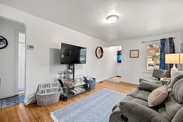 living room with arched walkways, baseboards, and wood finished floors