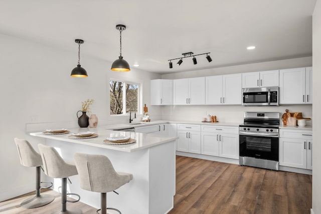 6712 C Highway 291, Nine Mile Falls, WA 99026 - kitchen featuring appliances with stainless steel finishes, white cabinetry, a peninsula, a breakfast bar area, and decorative light fixtures