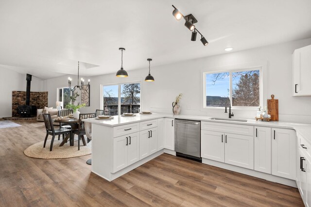 6712 C Highway 291, Nine Mile Falls, WA 99026 - kitchen featuring dishwasher, a sink, wood finished floors, a wood stove, and a peninsula