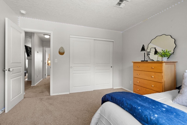 bedroom featuring baseboards, visible vents, a closet, a textured ceiling, and light colored carpet