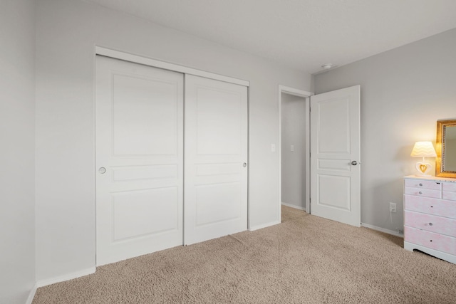 unfurnished bedroom with carpet flooring, baseboards, and a closet