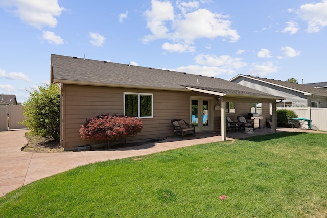 back of property featuring a lawn, fence, french doors, roof with shingles, and a patio area