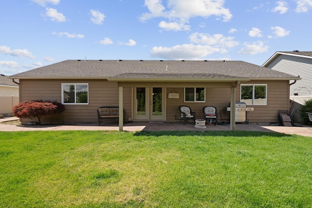 back of property featuring fence, a lawn, a shingled roof, and a patio area