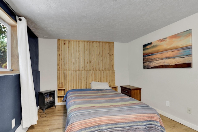 12017 E Mansfield Avenue ., Spokane Valley, WA 99206 - bedroom featuring a textured ceiling, a wood stove, baseboards, and wood finished floors