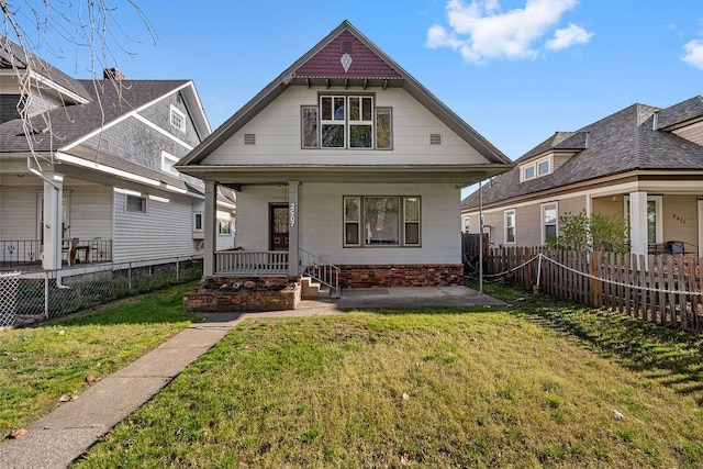 view of front of property with a fenced backyard, a front lawn, and covered porch