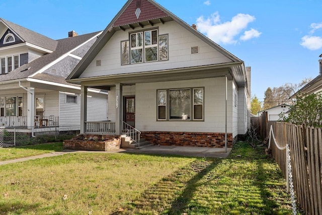 view of front of home with a fenced backyard, a front yard, and covered porch