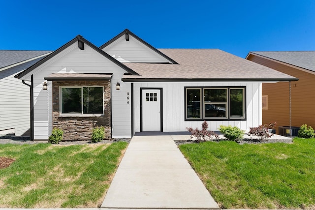 806 W Bolan Ave, Spokane, WA 99224 - view of front of property with roof with shingles, a front lawn, board and batten siding, cooling unit, and stone siding