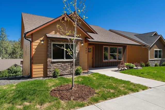 806 W Bolan Ave, Spokane, WA 99224 - view of front facade with stone siding, a front lawn, roof with shingles, and board and batten siding