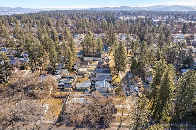 aerial view of property and surrounding area with nearby suburban area, a forest, and a mountainous background