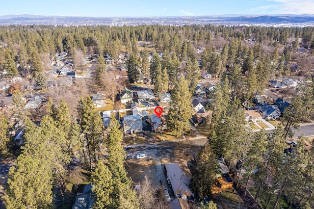 aerial overview of property's location with a heavily wooded area, nearby suburban area, and a mountainous background