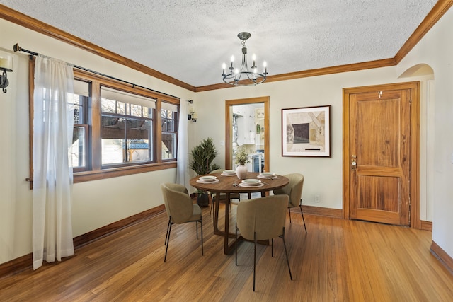 dining room featuring a textured ceiling, baseboards, light wood finished floors, a chandelier, and ornamental molding
