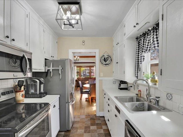 kitchen featuring appliances with stainless steel finishes, a chandelier, a sink, and decorative backsplash