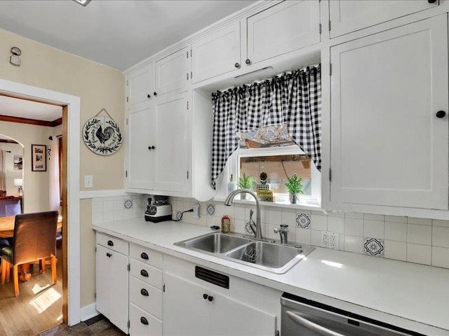 kitchen featuring dishwasher, a sink, white cabinetry, light countertops, and crown molding