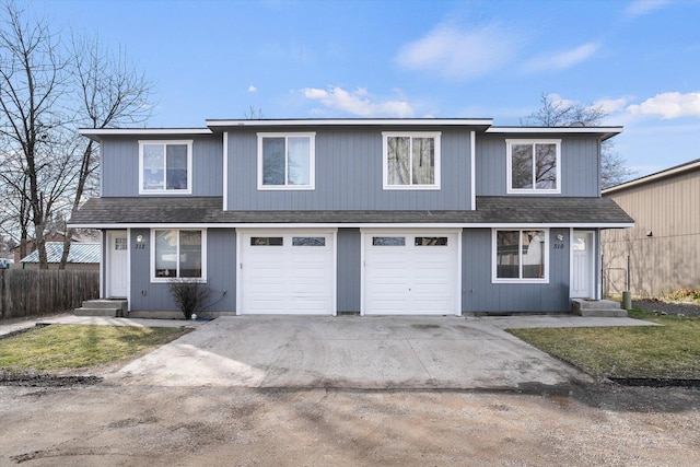 traditional-style house featuring concrete driveway, fence, a garage, and a shingled roof